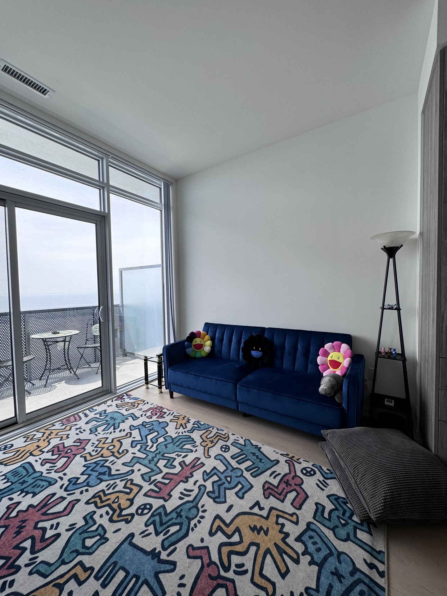 Den with Murakami flower pillows on blue velvet sofa